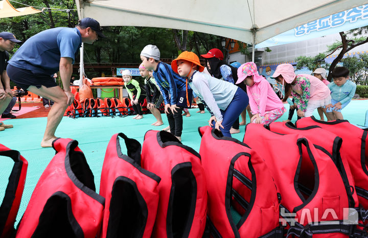 [서울=뉴시스] 황준선 기자 = 지난해 서울 송파구 송파안전체험교육관을 찾은 어린이들이 해양경찰대원들에게 생존수영을 배우기에 앞서 준비운동을 하고 있다. 2024.08.06. hwang@newsis.com