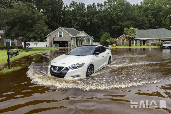 [AP/뉴시스] 미 조지아주 풀러에서 7일 한 주민이 이틀 전 열대폭풍 데비의 호우로 침수된 집앞 도로를 빠져나와 차로 출근하고 있다
