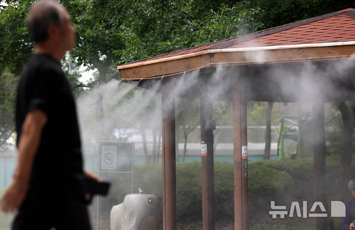 [광주=뉴시스] 광주지역에 폭염특보가 20일째 이어지고 있는 8일 광주 북구 우산근린공원 내 정자에 설치된 쿨링포그(안개형 냉각수) 아래로 시민들이 지나가고 있다. (사진 = 광주 북구 제공) 2024.08.08. photo@newsis.com