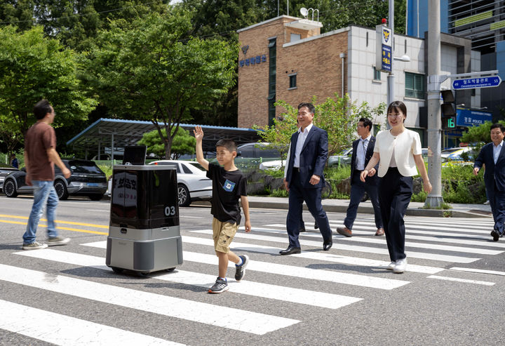 [서울=뉴시스] 이영환 기자 = 현대차·기아 로보틱스랩 자율주행 배송로봇이 9일 경기도 의왕시 부곡파출소 앞 횡단보도에서 시민과 함께 이동하고 있다. (사진=현대차·기아 제공) 2024.08.09. photo@newsis.com *재판매 및 DB 금지