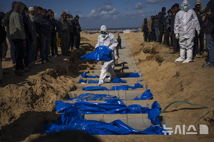 FILE - Palestinians bury the bodies of people who were killed in fighting with Israel and returned to Gaza by the Israeli military, during a mass funeral in Rafah, Gaza Strip, Tuesday, Jan. 30, 2024. (AP Photo/Fatima Shbair, File)