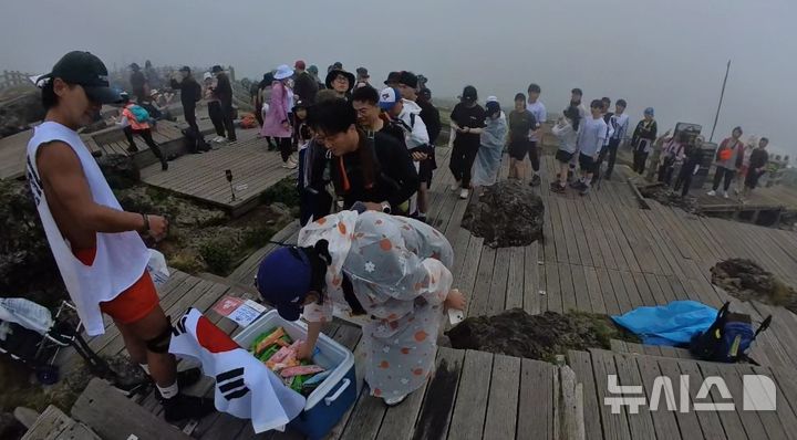 [제주=뉴시스] 광복절인 15일 오후 제주 한라산 정상에서 (왼쪽)조신홍씨와 곽용준씨가 아이스크림 나눔 활동을 하고 있다. (사진=독자 제공) 2024.08.15. photo@newsis.com