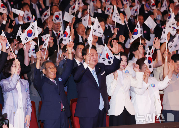 [서울=뉴시스] 조수정 기자 = 윤석열 대통령과 부인 김건희 여사가 15일 서울 종로구 세종문화회관에서 열린 제79주년 광복절 경축식에서 태극기를 흔들며 만세삼창을 하고 있다. 2024.08.15. chocrystal@newsis.com