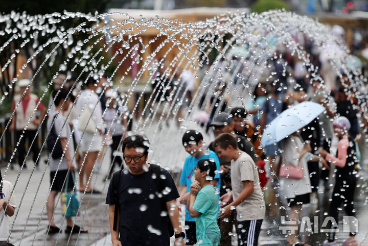 [서울=뉴시스] 배훈식 기자 = 무더위가 계속된 15일 오후 서울 종로구 광화문광장에서 시민들이 분수 터널을 걸으며 더위를 식히고 있다.  2024.08.15. dahora83@newsis.com