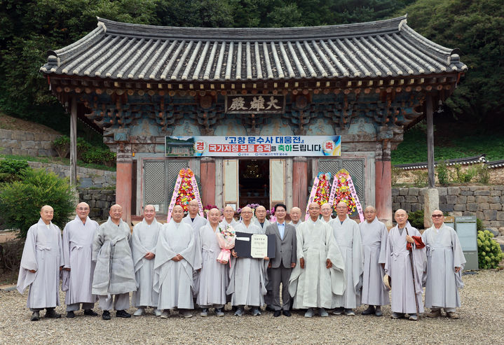 사찰 대웅전이 국가보물로 지정·승격된 고창 문수사에 고창군이 보물지정서를 전달했다. 심덕섭 군수와 문수사 주지 태효 스님을 비롯한 대한불교조계종 제24교구 내 사찰 스님들이 국가보물 문수사 대웅전을 배경으로 기념사진을 찍고 있다. *재판매 및 DB 금지