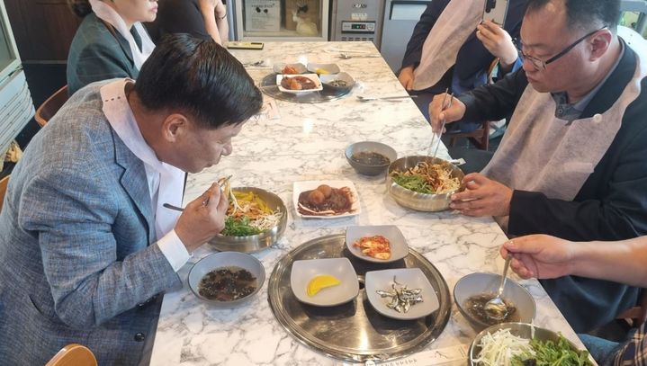 [고성(경남)=뉴시스] 경남 고성군은 22일 군이 발굴·보급하는 고성 대표먹거리인 '고성본전비빔우동'과 '고성팥물도넛'이 음식의 유래에 대한 이야기(스토리)가 담긴 영상 공개 이후 인기를 누리며 판매 중이라고 밝혔다. 사진은 이상근 고성군수(왼쪽)가 지난 21일 고성본전비빔우동과 고성팥물도넛을 시식하고 있는 모습. (사진=고성군 제공) 2024.08.22. photo@newsis.com *재판매 및 DB 금지