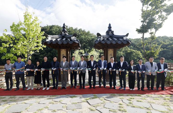 [울산=뉴시스] 22일 울산 남구 지산저수지 일원에서 '지산저수지 수변경관 조성사업 준공식'이 열린 가운데 서동욱 남구청장과 이상기 남구의회 의장, 시·구의원, 자생단체장, 주민 등이 기념 테이프를 자르고 있다. (사진=울산 남구 제공) 2024.08.22. photo@newsis.com *재판매 및 DB 금지