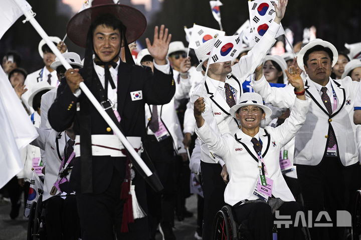 [파리=AP/뉴시스] 28일(현지시각) 프랑스 파리 콩코르드 광장에서 2024 파리 패럴림픽 개막식이 열려 대한민국 선수단의 기수 최용범(카누, 왼쪽)이 태극기를 들고 선수단과 함께 입장하고 있다. 2024.08.29.