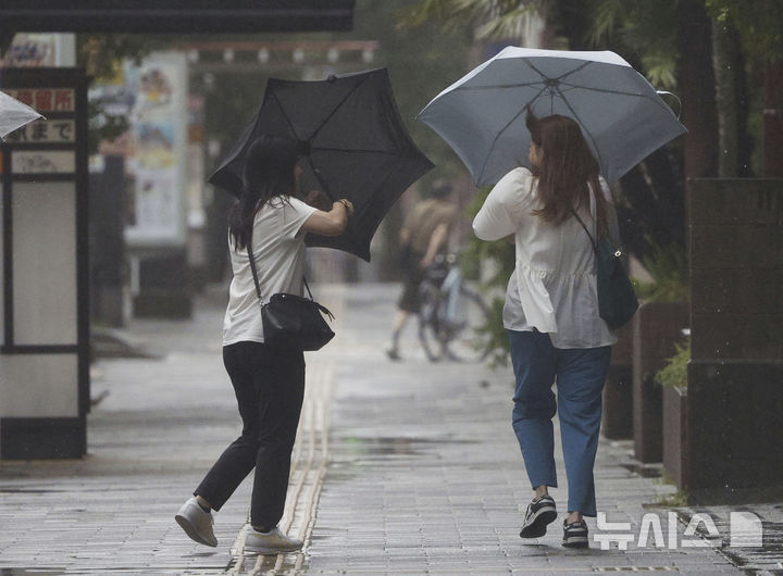 [가고시마=AP/뉴시스] 29일 일본 가고시마현 가고시마 거리에서 행인들이 제10호 태풍 산산의 영향으로 불어오는 강풍에 우산을 부여잡고 있다. 산산은 규슈 남부에 상륙한 것으로 알려졌다. 2024.08.29.