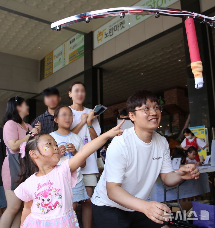 [청주=뉴시스] 서주영 기자 =  청주원도심골목길축제 '성안이즈백' 행사가 31일 오후 청주시 상당구 성안길 일대에서 열렸다. 시민들이 행사 게임코너에서 떨어지는 스틱을 잡는 게임인 '드랍스틱'을 즐기고 있다. 2024.08.31. juyeong@newsis.com