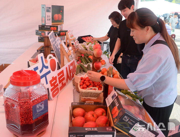 [장수=뉴시스] 김얼 기자 = 2024 RED FOOD FESTIVAL(제18회 장수 한우랑 사과랑 축제) 개막식이 열린 5일 전북 장수군 누리파크를 찾은 관광객들이 전시된 사과, 오미자 등 특산품을 살펴보고 있다. 2024.09.05. pmkeul@newsis.com