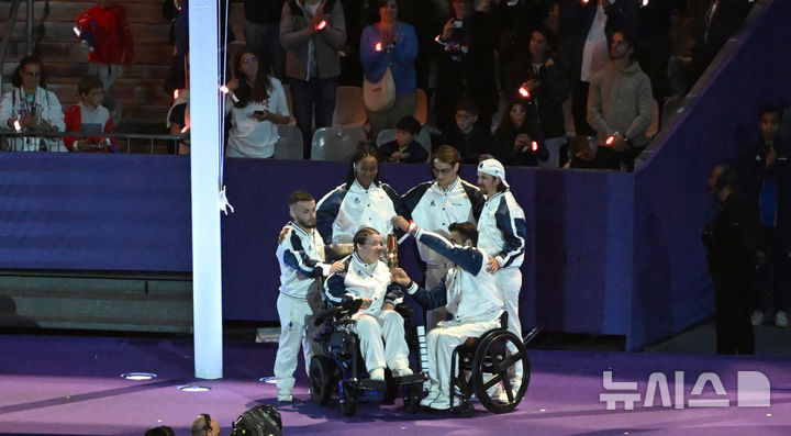 [생드니(프랑스)=공동취재단]프랑스 보치아 선수 오렐리 오베리(가운데)가 9일(한국시간) 프랑스 파리 인근 생드니 스타드 드 프랑스에서 열린 2024 파리 패럴림픽 폐회식에서 성화 불씨를 끄고 있다. (사진=대한장애인체육회 제공)