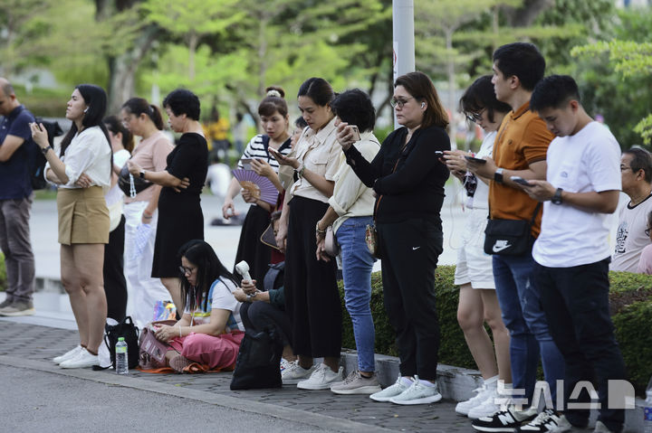 [싱가포르=AP/뉴시스] 12일 싱가포르 국립경기장에서 열린 프란치스코 교황 미사에 참석하지 못한 신자들이 경기장 밖에서 휴대폰 실시간 스트리밍으로 강연을 듣고 있다. 2024.09.13.