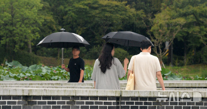 [전주=뉴시스] 김얼 기자 = 전국적으로 선선한 날씨가 이어지고 있는 20일 전북 전주시 전주덕진공원을 찾은 시민들이 우산으로 비를 피하며 길을 지나고 있다. 2024.09.20. pmkeul@newsis.com