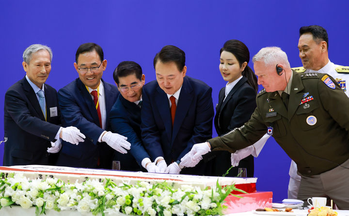 [서울=뉴시스] 조수정 기자 = 윤석열 대통령과 부인 김건희 여사가 1일 성남 서울공항 국빈행사장에서 열린 건군 제76주년 국군의날 경축연에서 축하 떡케이크를 자르고 있다. 왼쪽부터 김관진 국방혁신위 부위원장, 주호영 국회부의장, 김용현 국방부 장관, 윤 대통령, 김 여사, 폴 러캐머라 주한미군사령관, 김명수 합참의장. (사진=대통령실 제공) 2024.10.01. photo@newsis.com *재판매 및 DB 금지