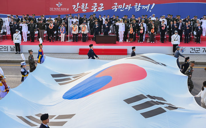 [서울=뉴시스] 최진석 기자 = 윤석열 대통령이 건군 76주년 국군의날 시가행진이 열린 1일 서울 광화문 광장 관람 무대에서 대형 태극기가 지나가자 국기에 경례하고 있다. (사진=대통령실 제공) 2024.10.01. photo@newsis.com *재판매 및 DB 금지