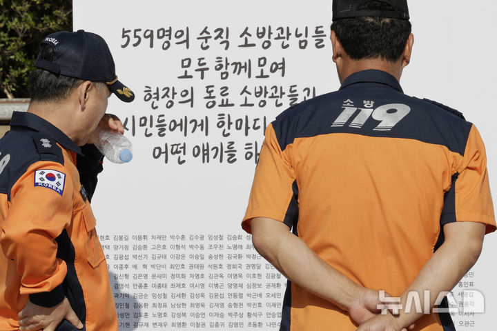 [평택=뉴시스] 최동준 기자 = 2024년 10월 5일 경기 평택 소방관이병곤길에서 열린 119메모리얼데이에서 소방관들이 순직 소방공무원을 기억하고 추모하는 작품을 살펴보고 있다. 2024.10.05. photocdj@newsis.com