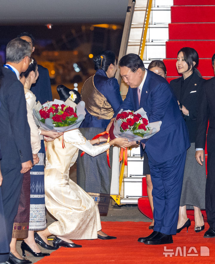 [비엔티안=뉴시스] 최진석 기자 = 아세안(ASEAN·동남아시아국가연합) 정상회의 참석차 라오스를 방문한 윤석열 대통령과 부인 김건희 여사가 9일(현지시각) 비엔티안 왓타이 국제공항에 도착해 1호기에서 내려 환영 인사로부터 꽃다발을 받고 있다. 2024.10.09. myjs@newsis.com