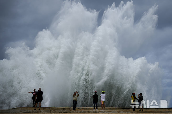 [아바나=AP/뉴시스] 9일(현지시각) 쿠바 수도 아바나에서 사람들이 허리케인 밀턴이 몰고 온 파도가 방파제에 부딪히며 생겨난 대형 물보라를 찍고 있다. 2024.10.10.