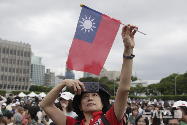 [타이베이=AP/뉴시스] 10일(현지시각) 대만 타이베이에서 제113주년 쌍십절 국경일 축하 행사가 열려 대만기를 든 남성이 총통 관저 앞에서 셀카를 찍고 있다.&nbsp; 2024.10.10.