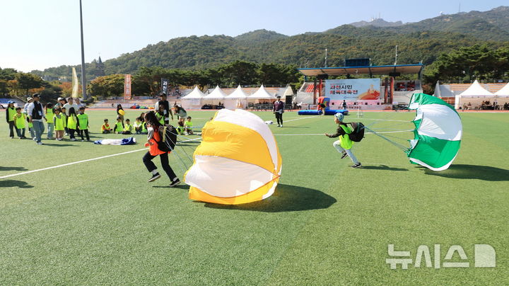 [과천=뉴시스] 체육대회에 참석한 어린이들이 가족들과 함께 '낙하산 달리기'를 하고 있다. (사진=과천시 제공).  2024.10.12. photo@newsis.com. *재판매 및 DB 금지 