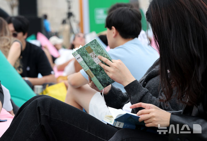 [서울=뉴시스] 김명원 기자 = 13일 서울 종로구 광화문 광장 서울 야외도서관 책마당에서 한강 작가의 노벨문학상 수상을 축하하기 위한 마련된 특별 전시에서 시민들이 한강 작가의 책을 읽고 있다.  이번 특별전은 ‘책읽는 서울광장’과 ‘광화문 책마당’, ‘책읽는 맑은냇가’ 등 3곳에서 진행된다. ‘채식주의자’ ‘소년이 온다’ ‘검은 사슴’ ‘바람이 분다, 가라’ 등 도서 10종, 총 216권이 한국어를 비롯해 영어, 일본어, 중국어, 아랍어, 그리스어 등 20개 언어로 된 번역본을 함께 전시한다.  한강은 지난 2016년 한국인 최초로 세계 3대 문학상인 '부커상'을 받았고, 지난해에는 프랑스 4대 문학상인 '메디치상'을 수상했다. 2024.10.13. kmx1105@newsis.com