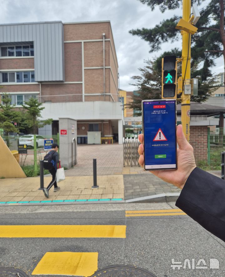 [부천=뉴시스] 정일형 기자 = 부천시 관내 초등학교 횡단보도에서 녹색신호 시 스마트폰 화면 차단 서비스가 실행되고 있다. (사진은 부천시 제공)