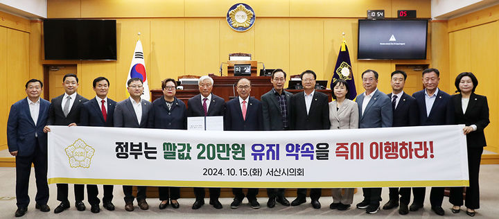 [서산=뉴시스] 15일 서산시의회 본회의장에서 의원들이 '쌀값 안정 대책 마련 촉구 건의안'을 만장일치로 채택한 후 관련 현수막을 들고 기념 촬영을 하고 있다. (사진=서산시의회 제공) 2024.10.15. *재판매 및 DB 금지