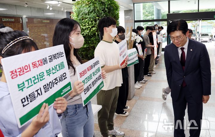 [부산=뉴시스] 하경민 기자 = 국회 교육위원회의 부산대, 경상국립대, 부산대병원, 부산대치과병원, 경상국립대병원 등 5개 기관에 대한 국정감사를 앞둔 18일 오후 부산 금정구 부산대  대학본부 로비에서 '부산대학교 의과대학 비상대책위원회' 소속 학생과 교수 등이 조건없는 휴학 승인 등을 촉구하는 피켓 시위를 연 가운데 국민의힘 조정훈 감사반장이 학생들에게 인사하고 있다. 2024.10.18. yulnetphoto@newsis.com