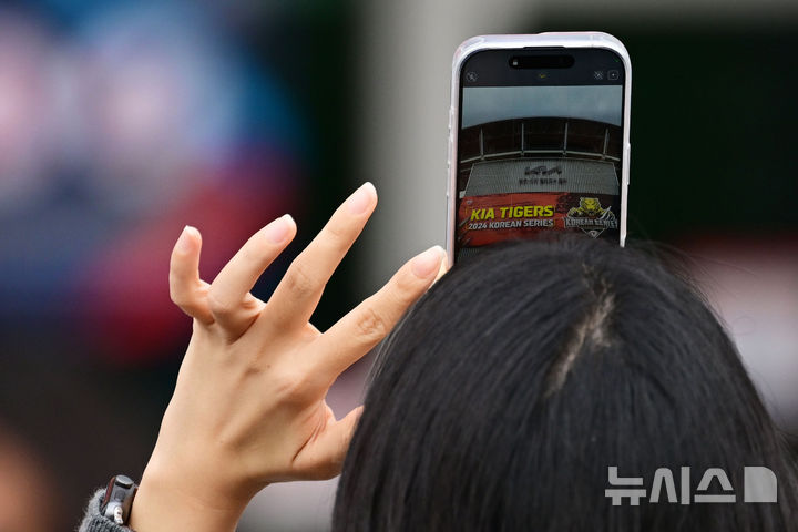 [광주=뉴시스] 이영주 기자 = 2024 신한 쏠뱅크 KBO 한국시리즈 5차전이 열리는 28일 오후 광주 북구 광주-기아챔피언스 필드에서 한 야구 팬이 경기 시작을 기다리며 경기장에 내걸린 현수막을 촬영하고 있다. 2024.10.28. leeyj2578@newsis.com