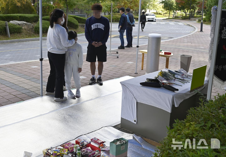 [광주=뉴시스] 박기웅 기자 = 31일 초등학생이 후진하던 폐기물 수거차량에 치여 숨진 광주 북구 신용동 모 아파트 단지 내 사고 현장에서 시민들이 국화와 과자를 올려놓으며 추모하고 있다. 2024.10.31. pboxer@newsis.com