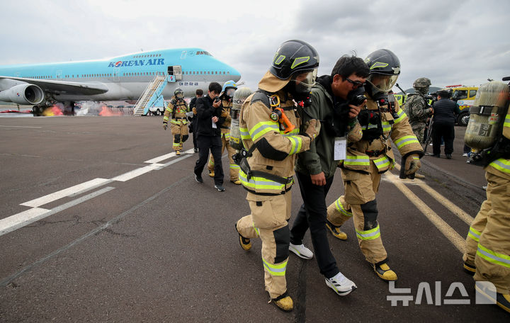 [제주=뉴시스] 우장호 기자 = 31일 오후 제주 도내 한 비행장에서 여객기 비상착륙에 의한 복합재난 상황을 가정해 열린 '2024 국가단위 긴급구조종합훈련'에 참가한 소방대원들이 환자를 옮기고 있다. 2024.10.31. woo1223@newsis.com