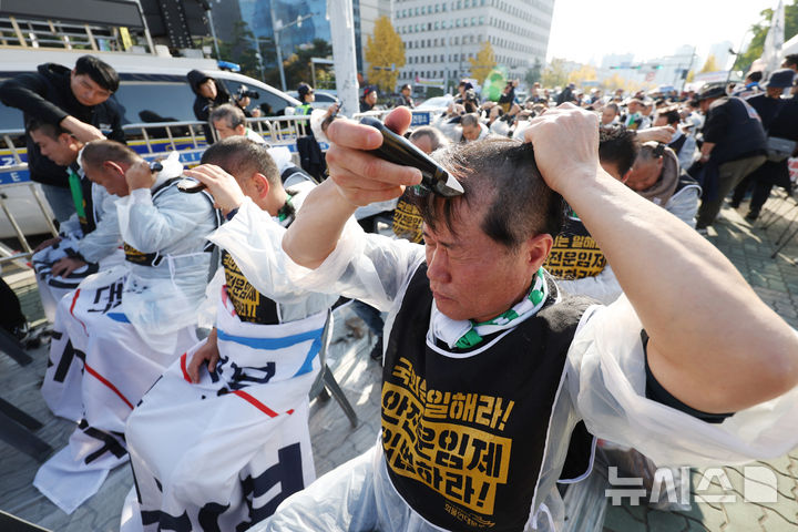 [서울=뉴시스] 김진아 기자 = 민주노총 공공운수노조 화물연대본부 조합원들이 11일 서울 여의도 국회 앞에서 '국민안전 사수! 안전운임제 입법 촉구! 화물노동자 100인 삭발 결의대회에서 삭발식을 하고 있다. 2024.11.11. photo@newsis.com