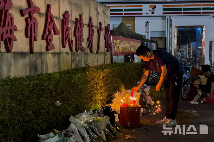 [주하이=AP/뉴시스] 12일(현지시각) 중국 남부 광둥성 주하이의 주하이 시민 체육관 광장에서 한 남성이 차량 돌진 희생자들을 위해 놓인 꽃다발 옆에 촛불을 밝히고 있다. 전날 저녁 60대 남성이 차량으로 시민을 향해 돌진, 35명이 숨지고 43명이 다친 것으로 알려졌다. 이 남성은 체육관 광장에서 운동 중이던 시민들을 들이받고 도주하다 공안에 체포됐다. 2024.11.13.