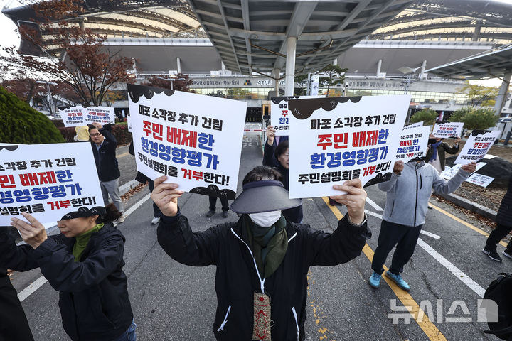 [서울=뉴시스] 김근수 기자 = 추가소각장 건립반대 범마포 다자협의체 회원들이 12일 서울 마포구 서울월드컵경기장 리셉션홀 앞에서 열린 서울시 광역자원회수시설 건립 환경영향평가(초안) 및 기후변화영향평가(초안) 주민설명회 반대 기자회견에서 구호를 외치고 있다. 2024.11.12. ks@newsis.com