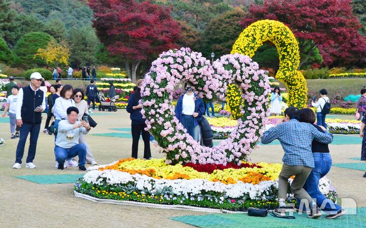 [청주=뉴시스] 서주영 기자 = 17일 충북 청주 청남대를 찾은 행락객들이 헬기장에서 국화 조형물을 배경으로 사진을 촬영하고 있다. 2024.11.17. juyeong@newsis.com