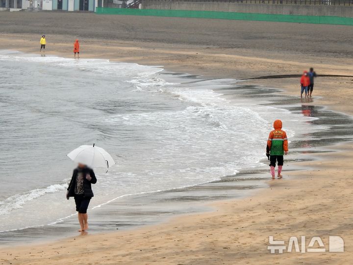 [제주=뉴시스] 오영재 기자 = 일요일인 1일은 전국에 구름이 많이 끼는 가운데 제주도에는 비가 내리겠다. 사진은 이슬비가 내리고 있는 지난 24일 오전 제주시 이호테우해변에서 우산과 우비를 쓴 방문객들이 맨발 걷기 활동인 '어싱'을 하고 있는 모습. 2024.11.24. oyj4343@newsis.com  