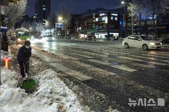 [서울=뉴시스] 정병혁 기자 = 눈이 내린 27일 서울 서대문구 홍제역 인근에서 상인이 눈을 치우고 있다. 2024.11.27. jhope@newsis.com