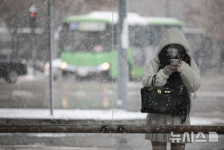 [서울=뉴시스] 정병혁 기자 = 27일 서울 용산구 용산역 인근에서 한 시민이 눈을 피해 택시를 기다리고 있다. 2024.11.27. jhope@newsis.com