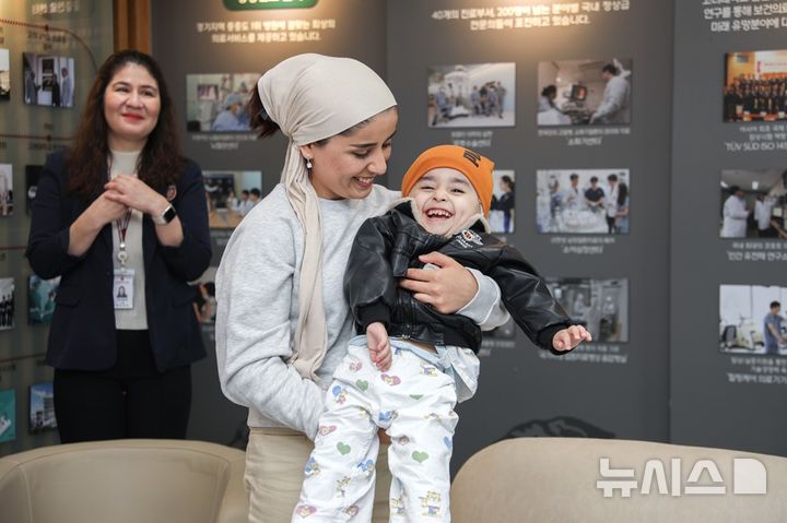 [서울=뉴시스]성공적으로 치료를 마치고 기뻐하는 무스타포군을 어머니가 웃으며 안아 올리고 있다. (사진= 고대안산병원 제공) 2024.11.29. photo@newsis.com. 