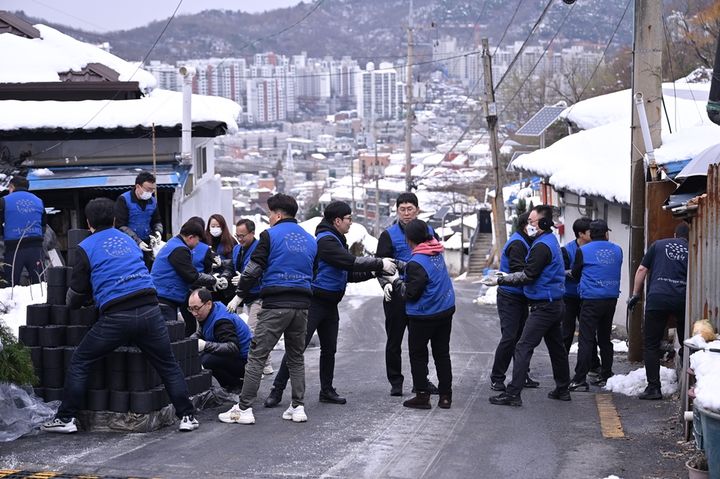 [서울=뉴시스] 지난 11월 29일 동문건설 임직원들이 기후환경 취약계층 가구에 기부한 연탄을 배달하고 있다. 2024.12.02 (사진제공=동문건설). photo@newsis.com *재판매 및 DB 금지