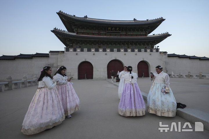 [서울=AP/뉴시스]미국에서 온 제시카 에르난데스(오른쪽 3번째)가 4일 한복을 입고 경복궁 관광에 나서 광화문 근처에서 사진을 찍고 있다. 한국은 물론 전 세계를 충격에 빠뜨렸던 윤석열 대통령의 비상계엄 선포에도 한국을 찾은 외국 관광객들은 여전히 서울 의 고궁들과 랜드마크, 쇼핑가들로 몰려드는 등 크게 동요하지 않았다. 2024.12.04. 