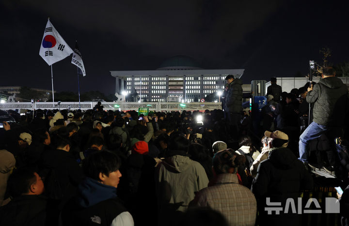 [서울=뉴시스] 김진아 기자 = 윤석열 대통령의 비상계엄 해제 요구 결의안이 국회 본회의에서 통과된 4일 새벽 서울 영등포구 국회 정문 앞에서 시민들이 윤석열 대통령 퇴진 촉구 구호를 외치고 있다. 2024.12.04. bluesoda@newsis.com