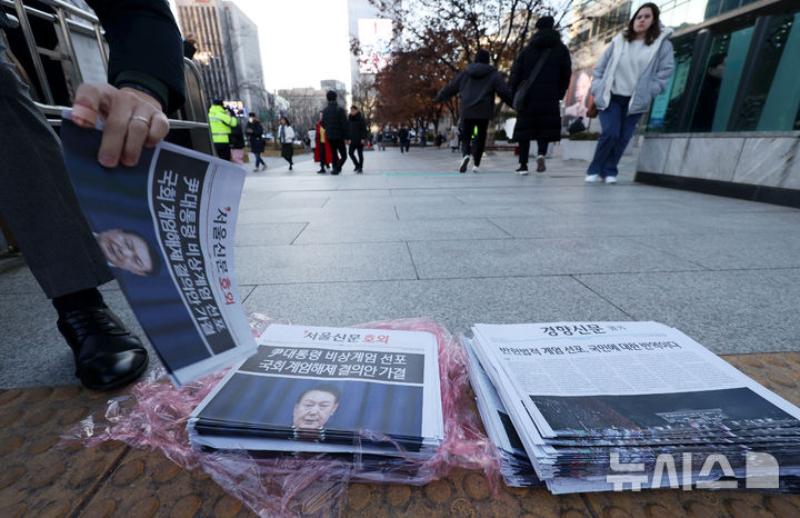 [서울=뉴시스] 홍효식 기자 = 윤석열 대통령이 비상계엄을 선포한 지 6시간여 만에 해제한 4일 서울 광화문역에서 한 시민이 비상계엄 관련 호외를 가져가고 있다. 2024.12.04. yesphoto@newsis.com