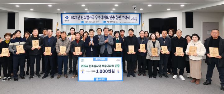 [대전=뉴시스] 조명휘 기자 = '2024년 탄소발자국 우수아파트'로 인증을 받은 대전 유성구 지역 아파트 관계자들이 인증패를 받은 뒤 기념촬영을 하고 있다. (사진= 유성구 제공) 2024.12.08. photo@newsis.com *재판매 및 DB 금지