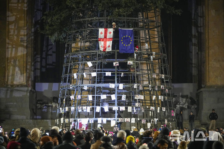 [트빌리시=AP/뉴시스] 2024년 12월 8일 조지아 트빌리시 의사당 앞에서 시위대가 인공 크리스마스트리에 조지아 국기, 유럽연합(EU) 깃발과 경찰 폭행으로 부상한 시위자들의 사진을 붙이고 있다. 2025. 01. 18.