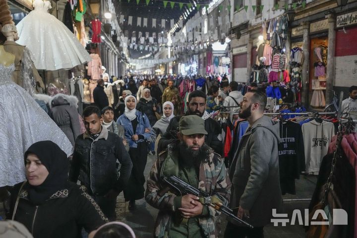 [AP/뉴시스] 10일 시리아 수도 다마스쿠스에서 반정부군 전사가 알하미디예 전통시장 거리를 사람들 틈에 끼어 걸어가고 있다.