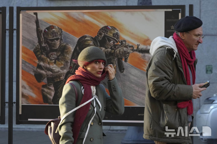 [상트페테르부르크=AP/뉴시스] 지난해 12월 11일(현지시각) 러시아 상트페테르부르크에서 시민들이 러시아 군대를 기리는 '함께 승리를 향해'라는 주제의 포스터 앞을 지나가고 있다. 2025.06.07.