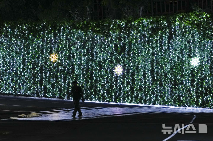 [파시그=AP/뉴시스] 11일(현지시각) 필리핀 파시그의 메랄코 리와나그 공원에서 한 남성이 크리스마스 조명 장식을 따라 걷고 있다. 2024.12.12.