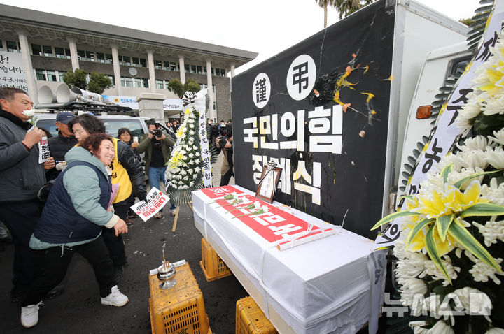 [제주=뉴시스] 우장호 기자 = 전국농민회총연맹 제주도연맹과 도내 진보정당 관계자들이 13일 오후 제주도의회 앞에서 열린 '내란수괴 윤석열 체포·구속! 내란공범 국민의힘 해체! 제주농민대회' 집회에서 국민의힘 장례식을 치르고 있다. 2024.12.13. woo1223@newsis.com